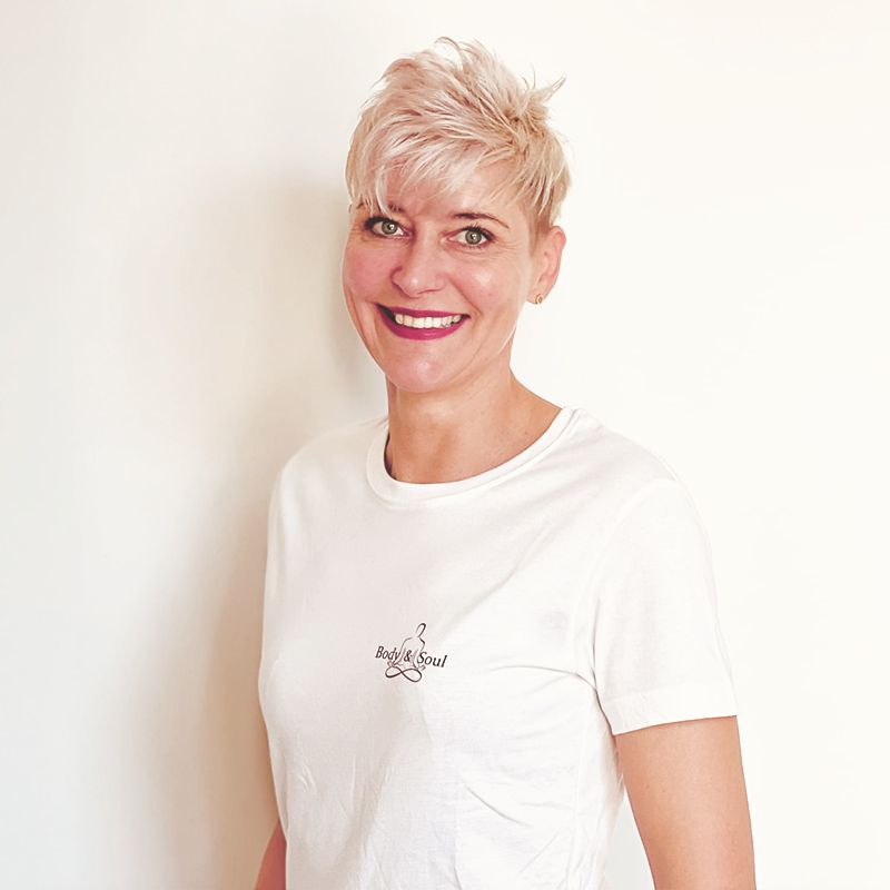 Eine Frau trägt ein weißes T-Shirt und lächelt.