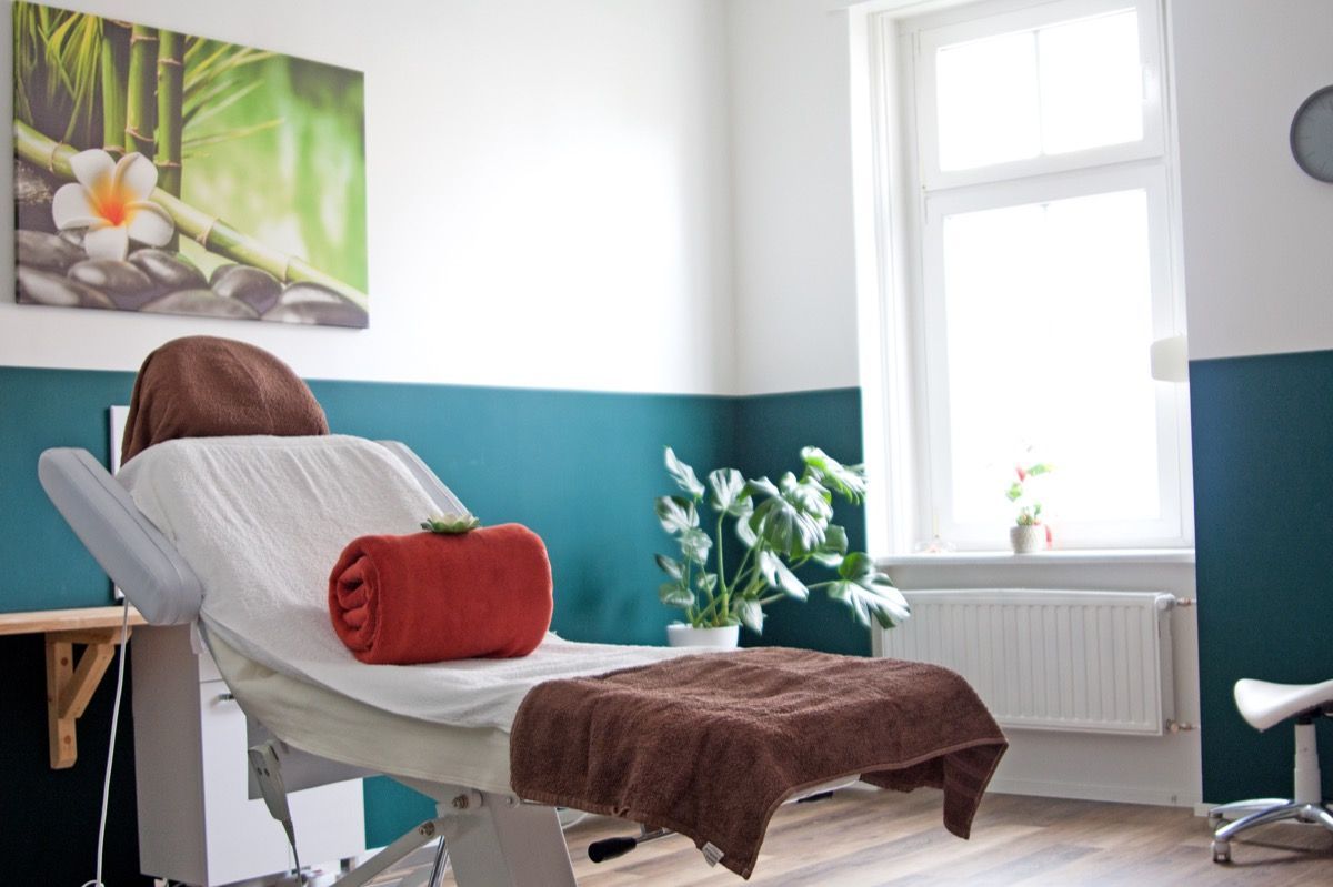 Ein Raum mit einem Massagetisch und einem Gemälde an der Wand.