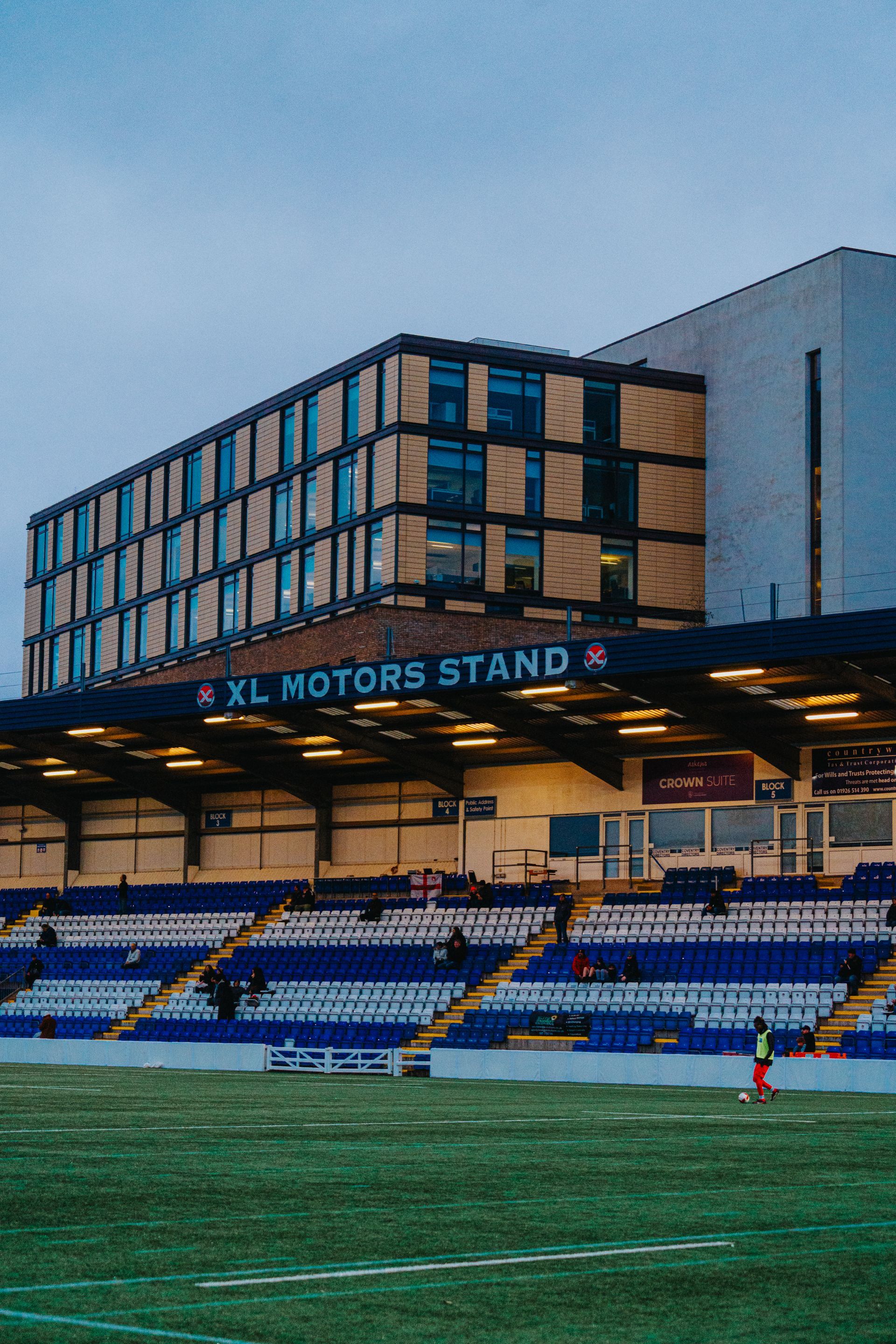A Football pitch with a building in the background that says xl motors stand