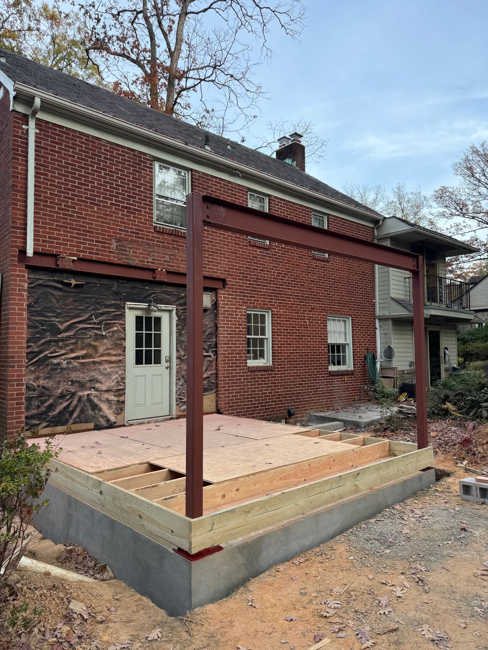 Construction of a brick house patio with red support beams.