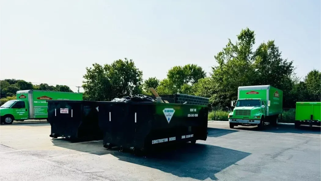 Green Diamond Disposal trucks and black dumpsters parked on an asphalt lot. Company name and phone number below.