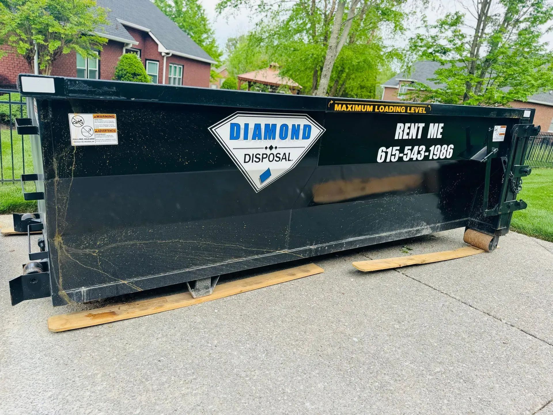 Black Diamond Disposal dumpster on a street, with white logo and phone number on the side.