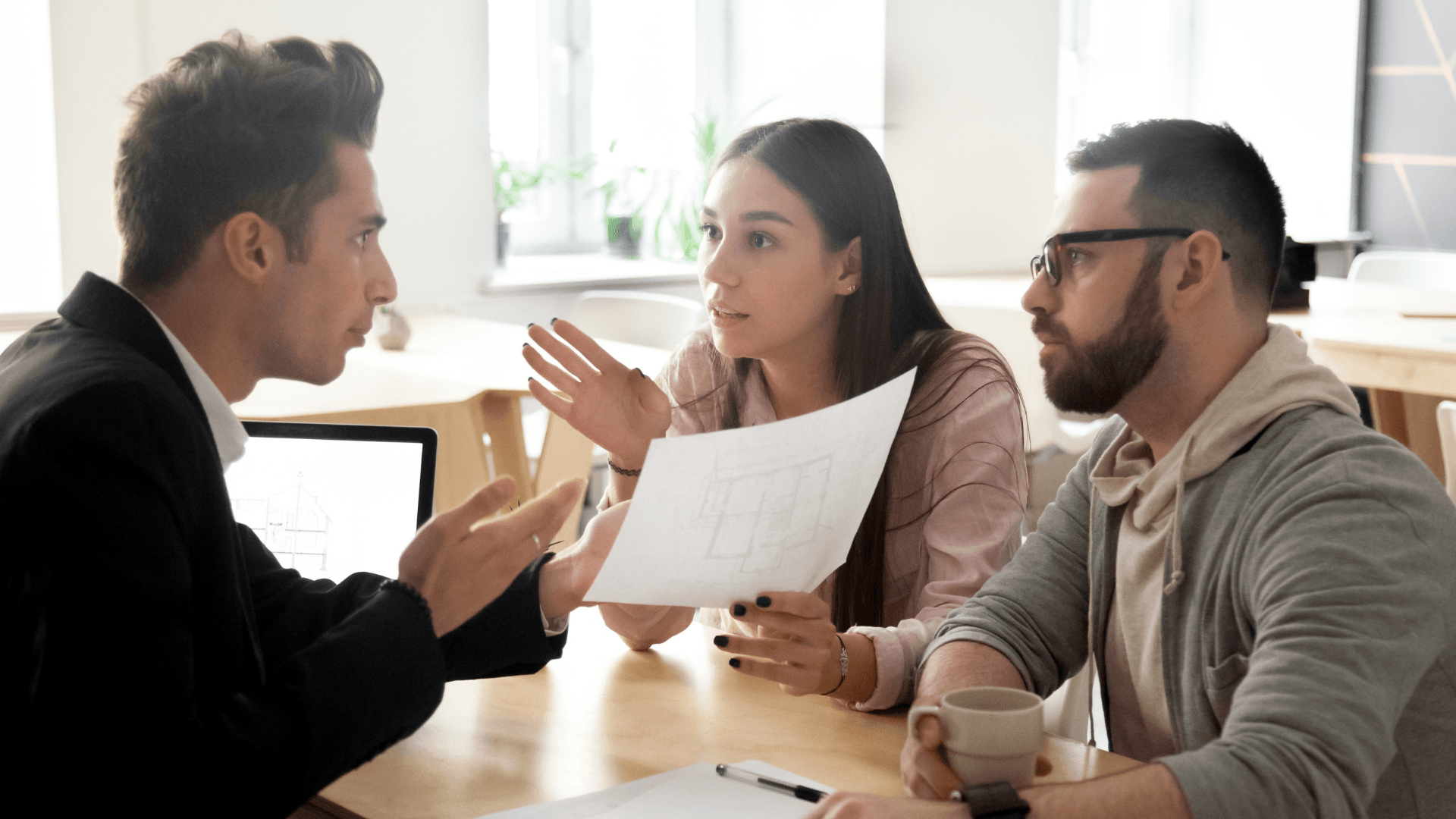 hree people sitting at a table with papers in front of them