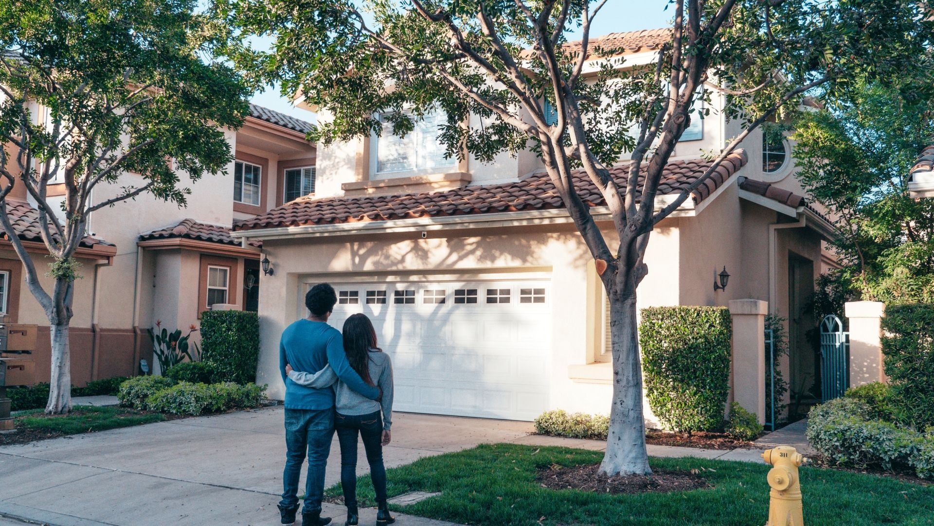 Couple viewing two-story suburban home with garage