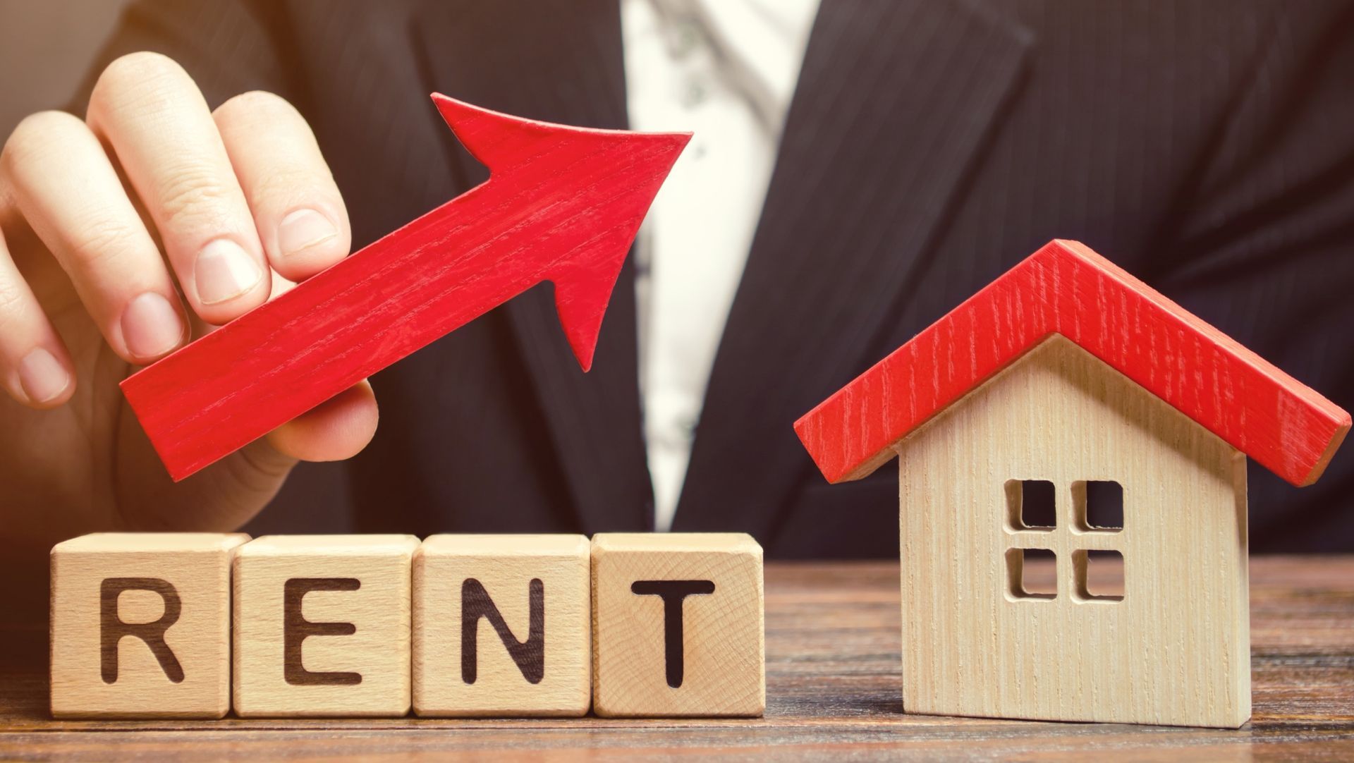 Image: 'Rent' spelled out in Scrabble blocks with a house on the right and a red arrow pointing to it