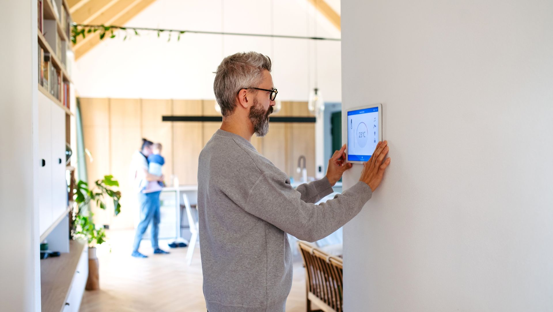 Man installing a smart thermostat in a rental property as a simple spring home upgrade to attract tenants.