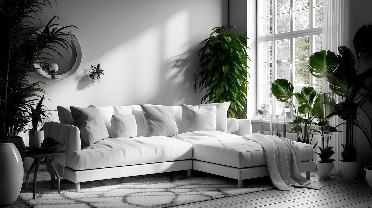 Bright modern living room with white sectional, plants, wall mirror, and large windows with natural light.