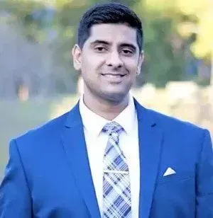 A man in a blue suit and tie is smiling for the camera.