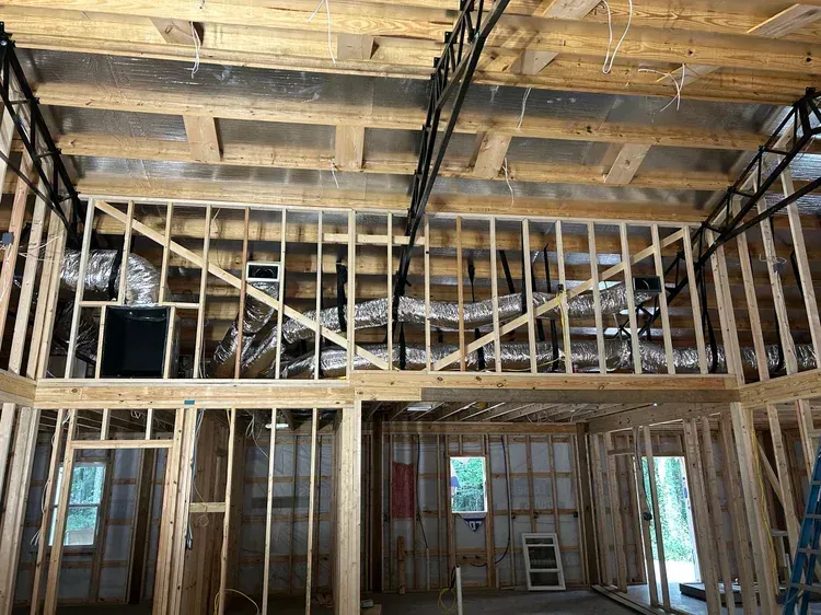 Interior of a house under construction with exposed wooden framing and unfinished ceiling