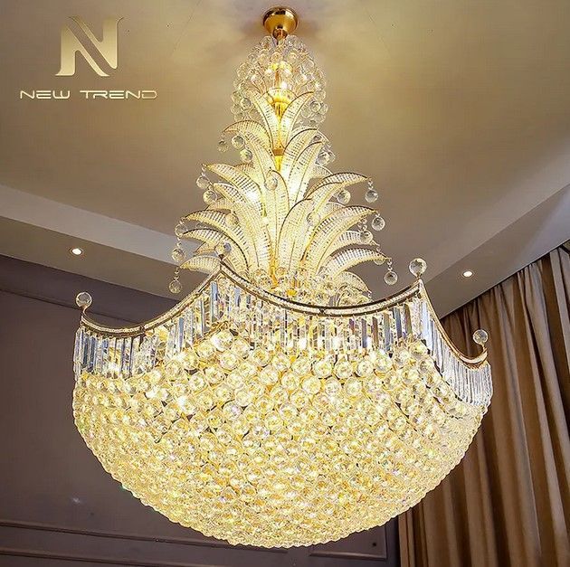 Gold crystal chandelier hanging from a beige ceiling, casting warm light.