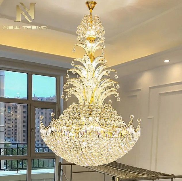 Gold crystal chandelier hanging from a beige ceiling, casting warm light.