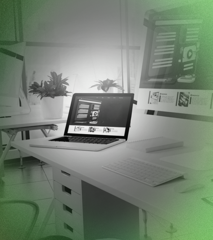 Laptop on white desk in modern office setting with computer and plants.
