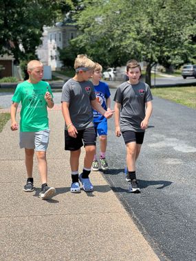 A group of young Loudoun Soccer boys are walking down a sidewalk.