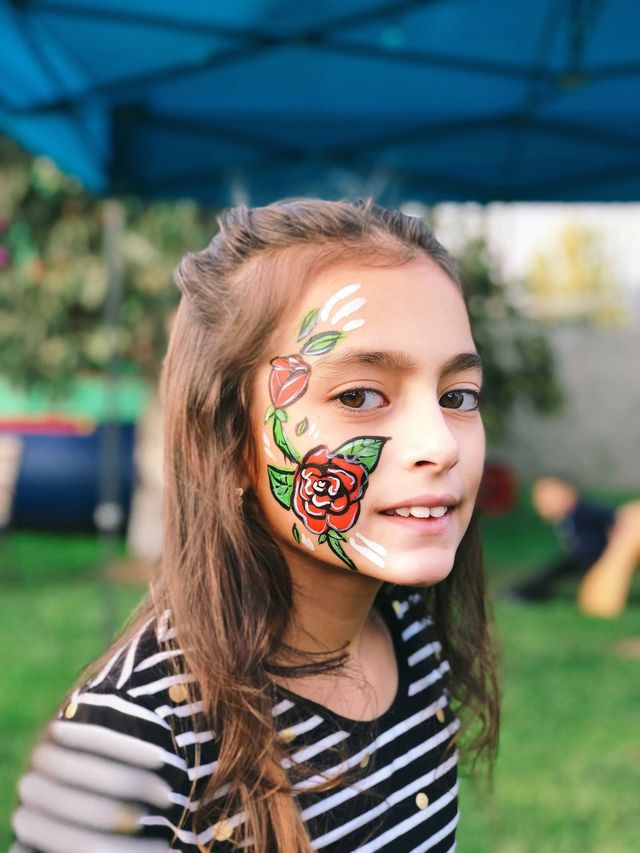 Rose cheek design face painting at an outdoor party
