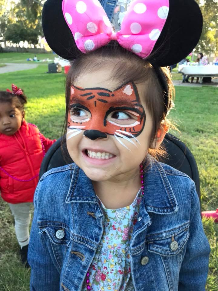 Tiger face painting on a girl wearing Minnie Mouse ears
