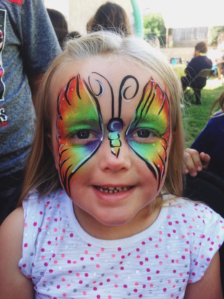 Rainbow butterfly face painting on a smiling girl