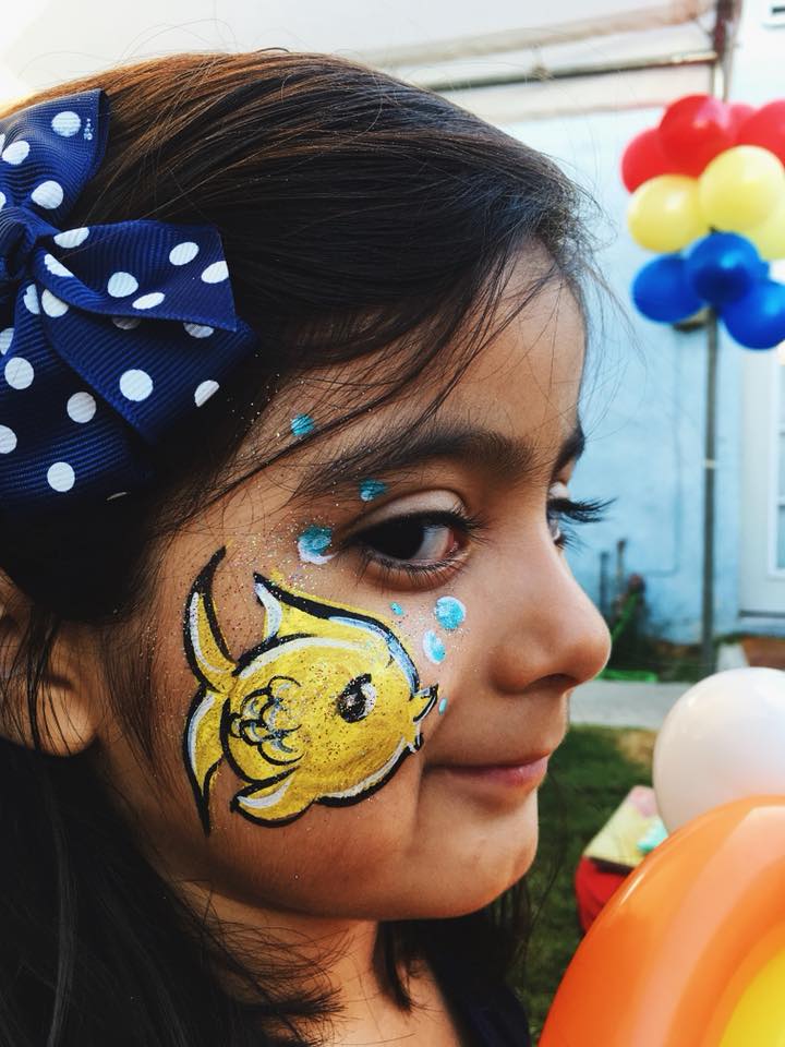 Yellow fish cheek design face painting on a girl