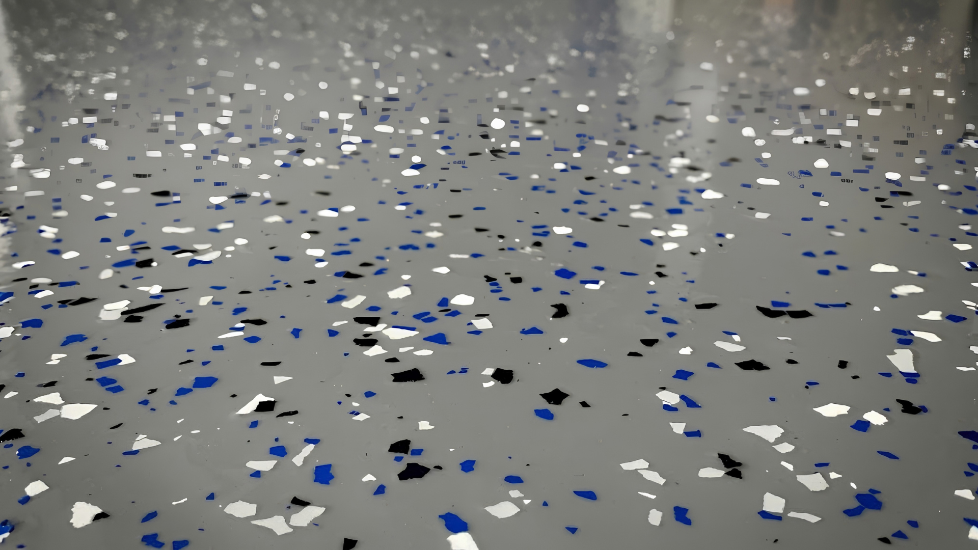 Scattered blue, white, and black confetti on a gray floor or tabletop.