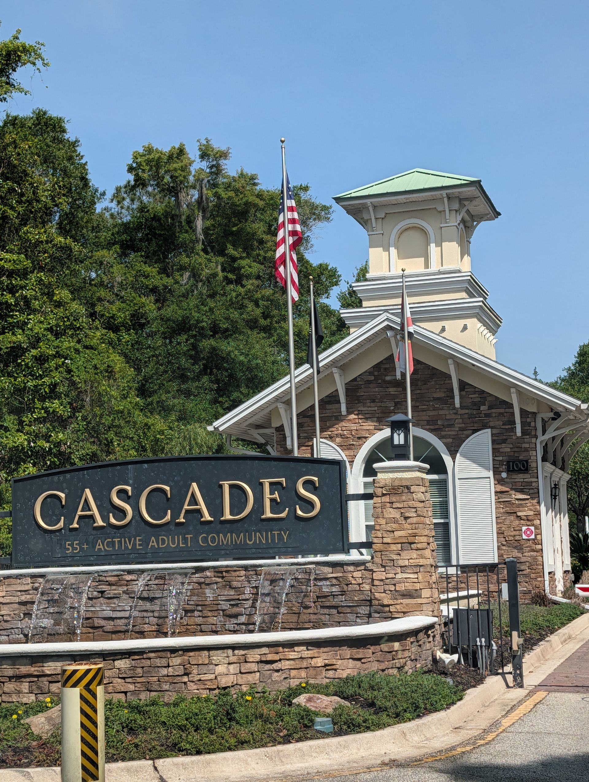 Cascades entrance sign and building with American flag under a green-roofed tower in sunny daylight