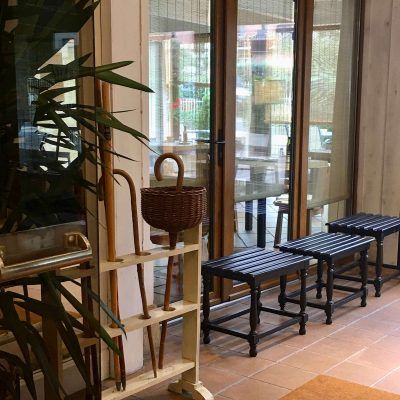 An interior shot with a row of black benches, a cane stand, and a glass door leading to a patio.