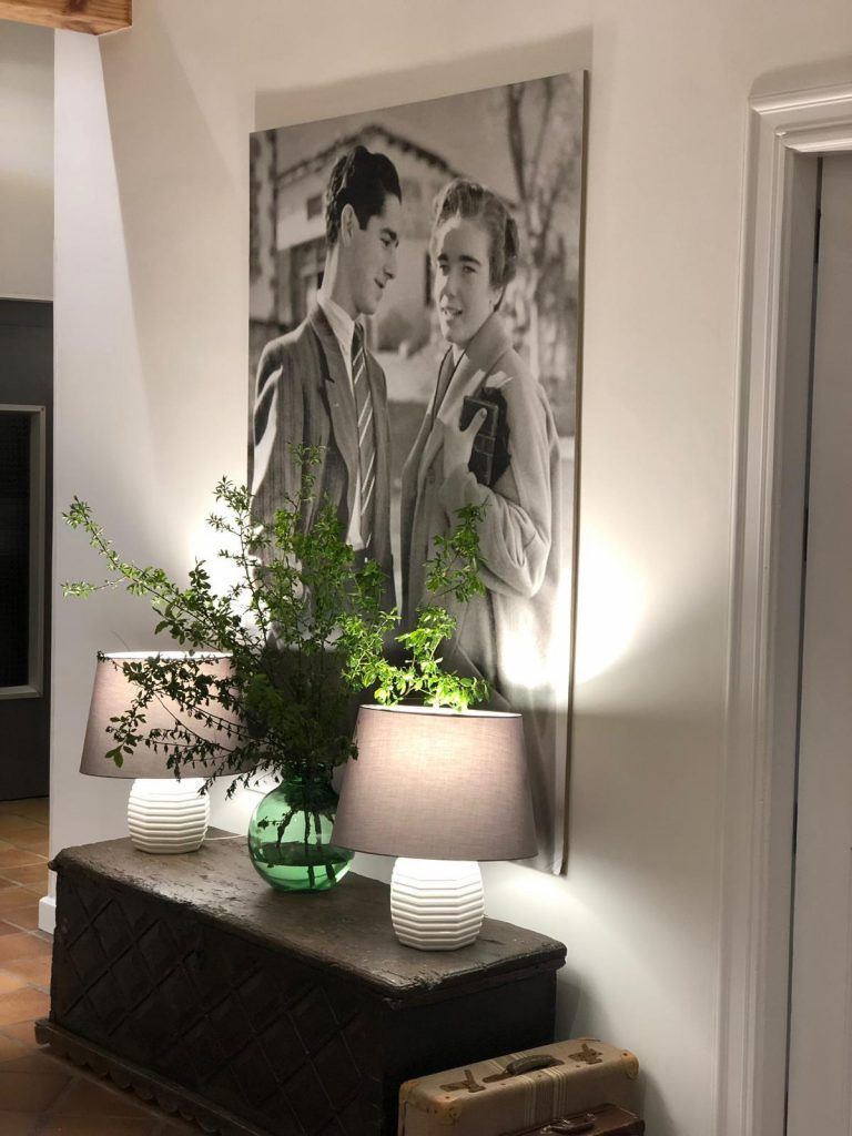 Black and white photo of a couple, above a wooden chest with lamps and greenery.