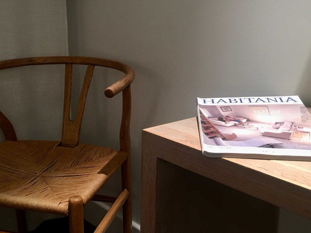 Wooden chair next to a small table with a magazine on top.
