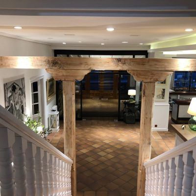 View from a staircase, leading to a hallway with tiled floor, wooden archway, and an entrance.