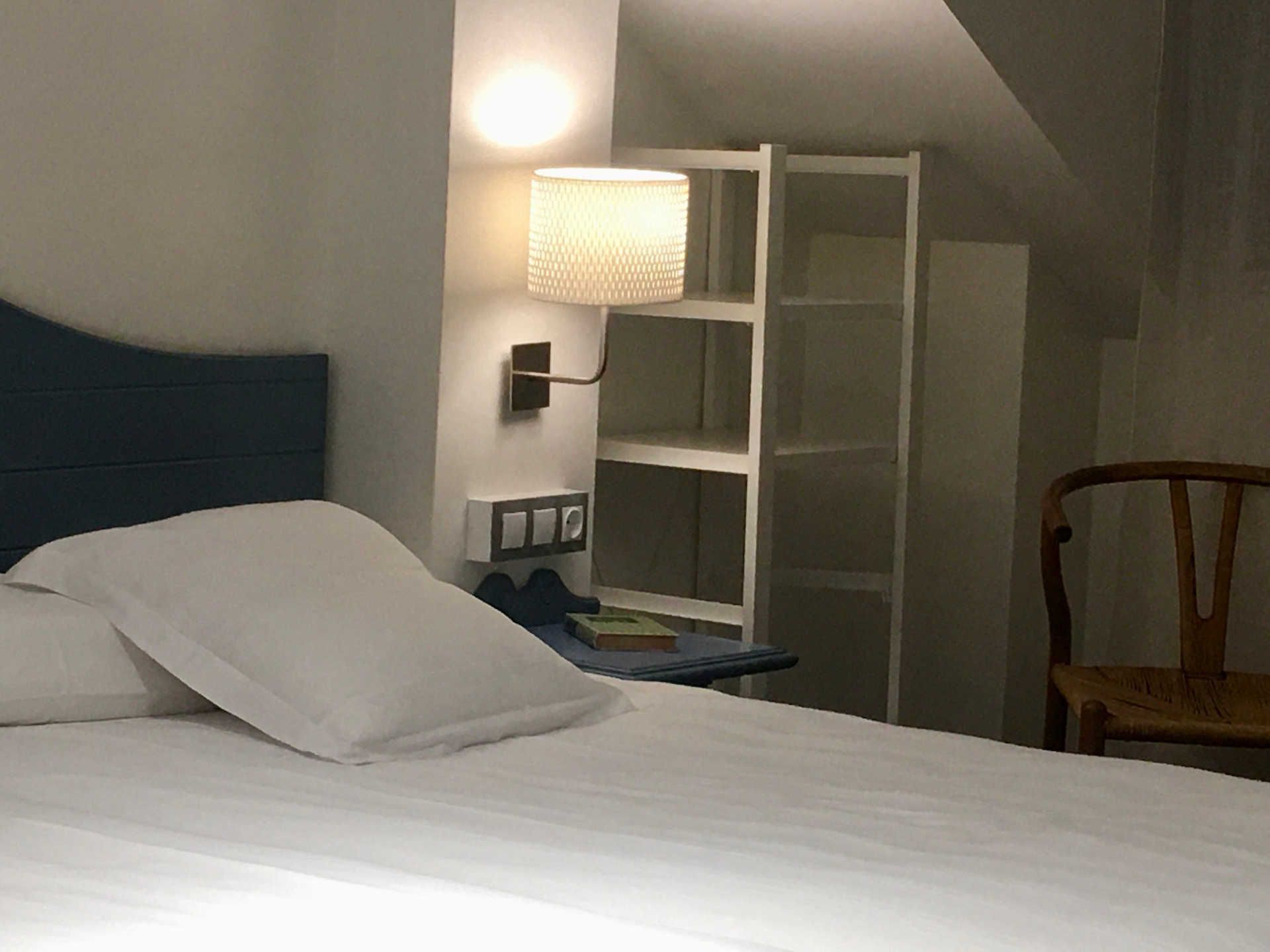 Bedroom with bed, blue headboard, lamp, and shelving.