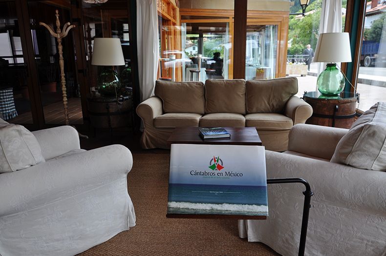Lounge area with beige sofas, lamps, a low table holding a menu, and a view to the outside.