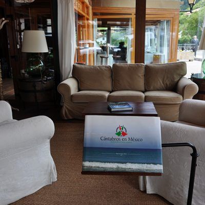 Cozy seating area with a sofa and two armchairs, a book on a side table, and a view of the outdoors.