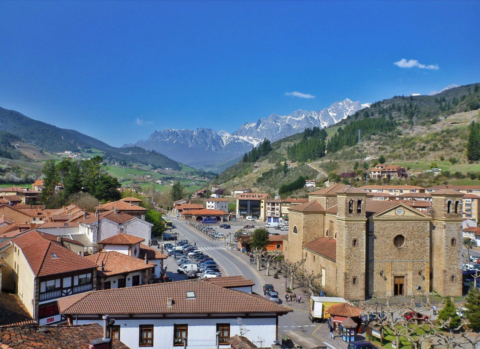 Townscape with church, buildings, road, mountains, and blue sky.