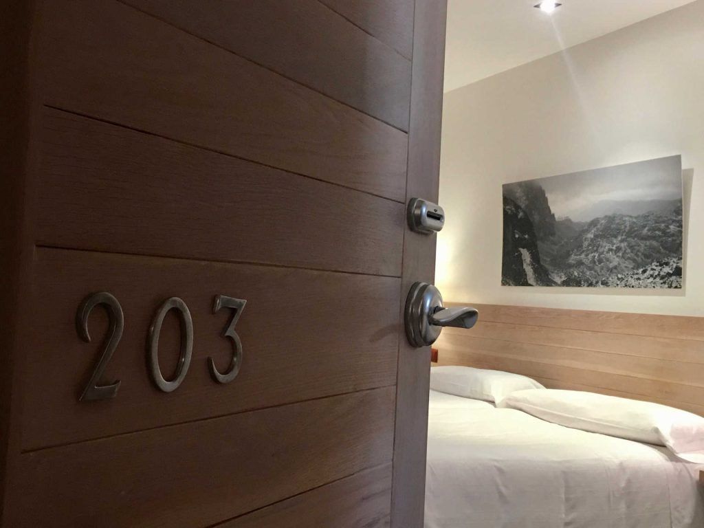 Hotel room door open, number 203 visible. Bed and artwork seen inside.