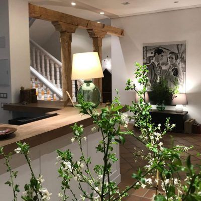 Reception desk with flowers, light, staircase, and artwork in a cozy interior.