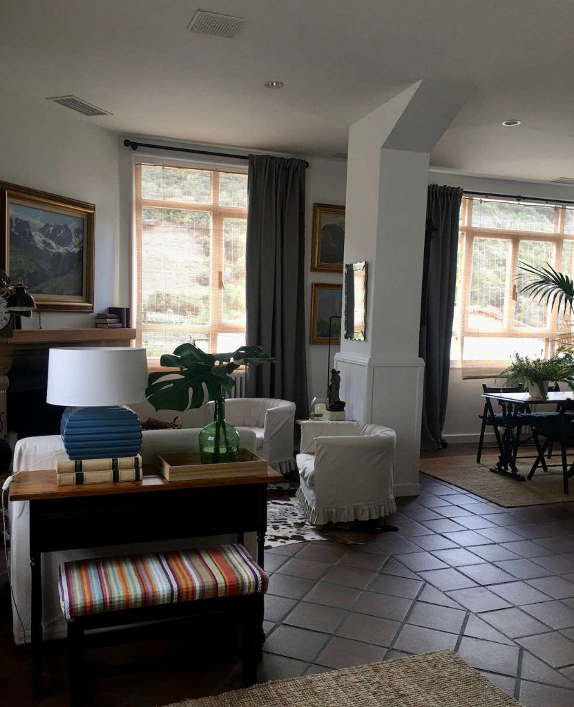 Living room with arched windows, white walls, dark curtains, and a mix of furniture.