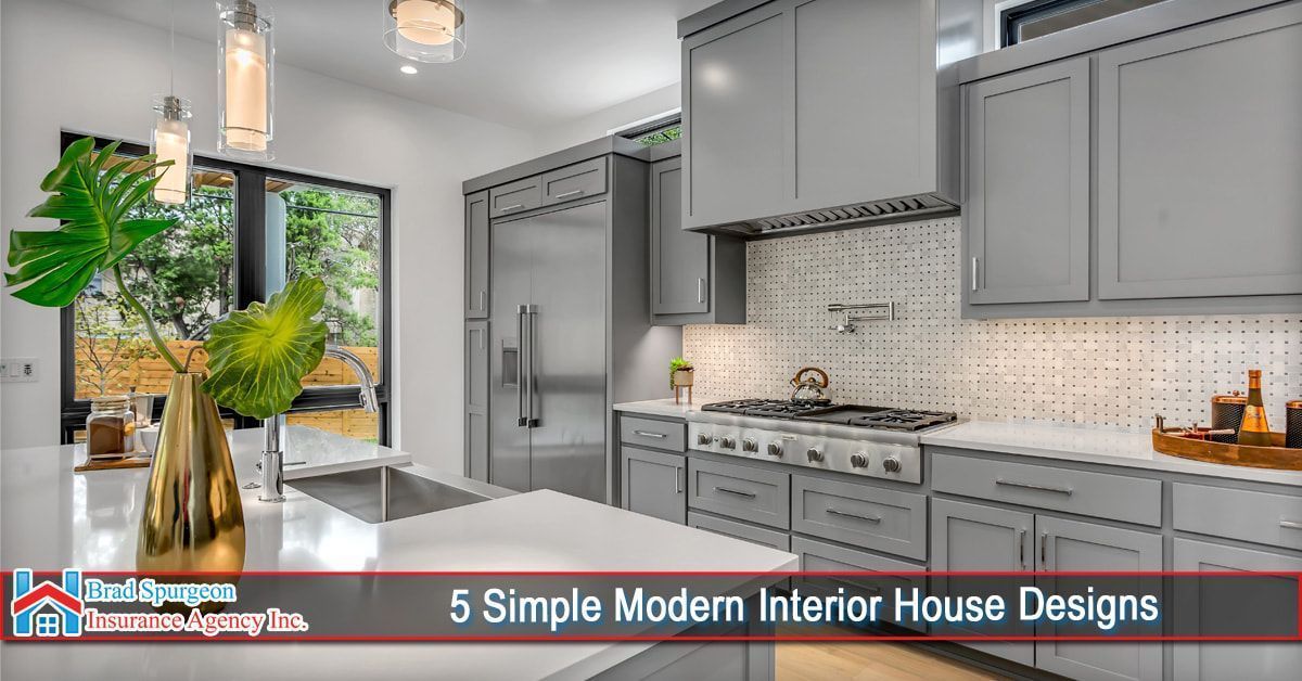 A modern kitchen with grey cabinets, a stainless steel range, white countertops, and a vase with large green leaves.