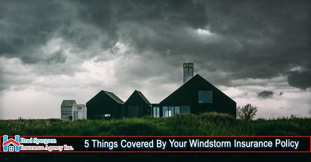 Dark storm clouds loom over a modern home in a grassy field