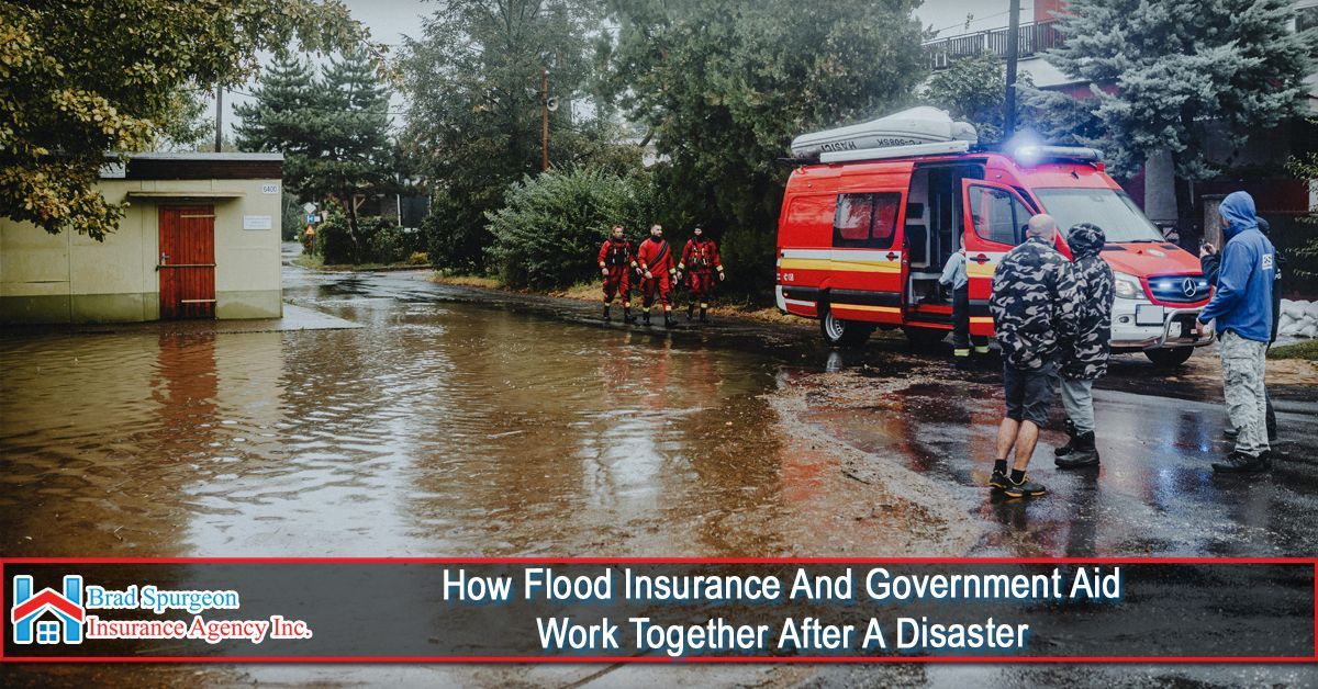 Emergency responders stand by a red rescue vehicle on a street flooded with brown water after a disaster.