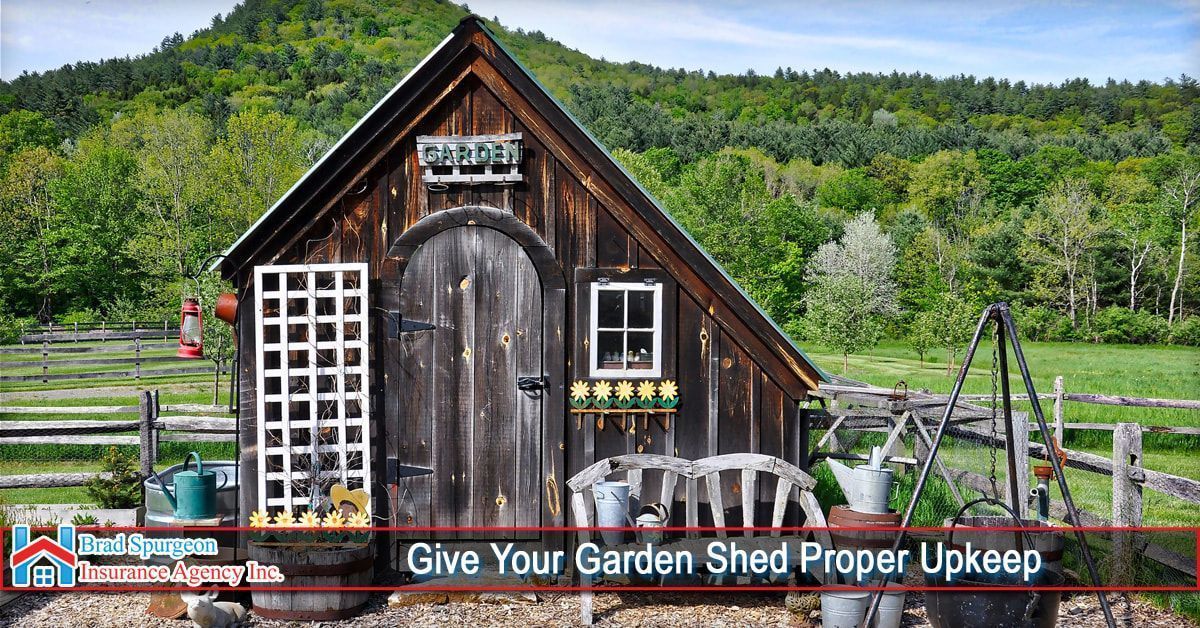 A weathered wooden garden shed with a white trellis and bench, set against a green, rolling mountain landscape.