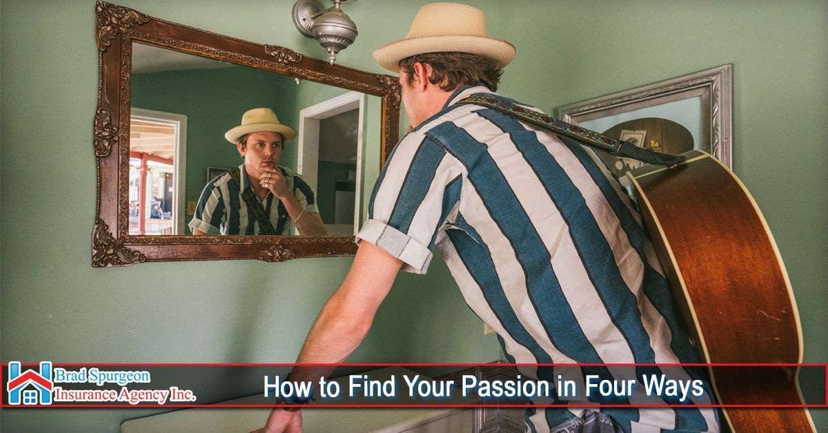 A person wearing a hat and striped shirt looks at their reflection in a mirror while holding an acoustic guitar.
