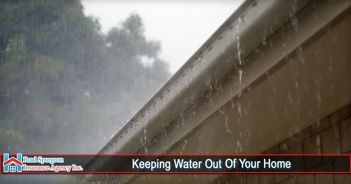 Rainwater overflows from a residential metal gutter during a heavy rainstorm.