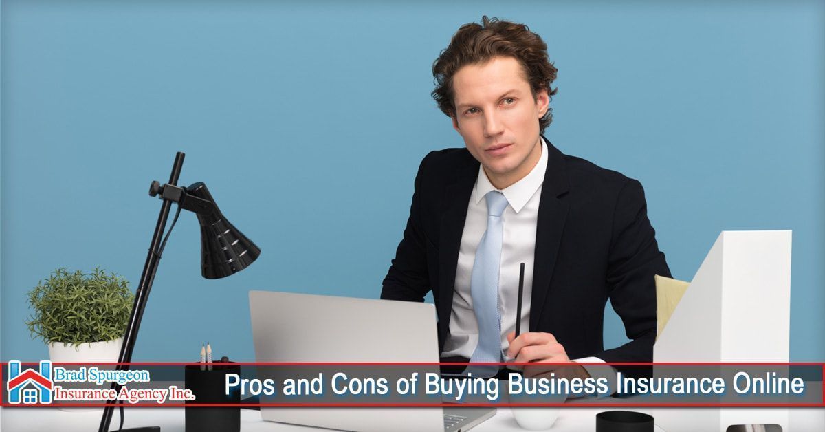 A person in a suit sits at a desk with a laptop and lamp