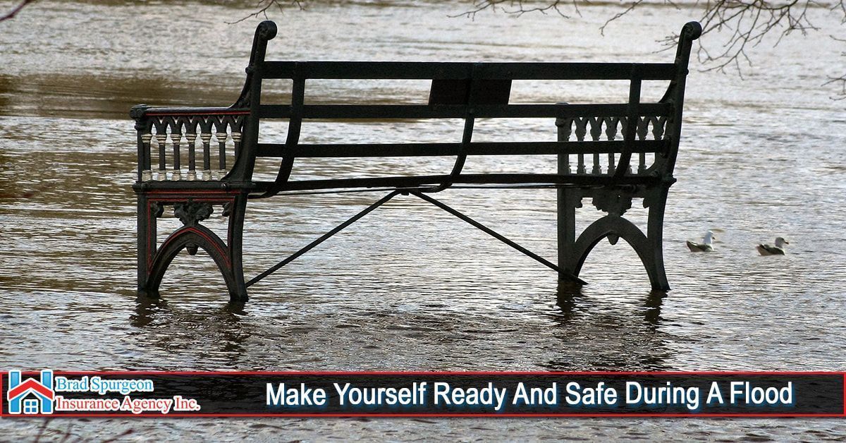 A black park bench sits partially submerged in floodwaters