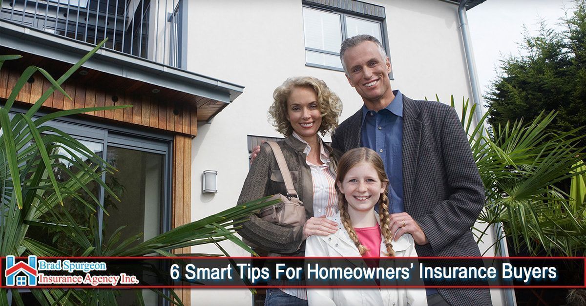 A family stands smiling in front of their home 
