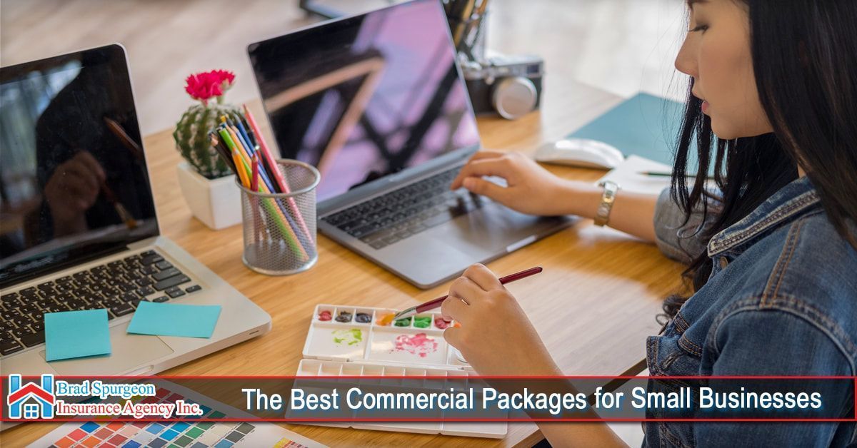 A person works at a desk with two laptops, a watercolor set, and art supplies