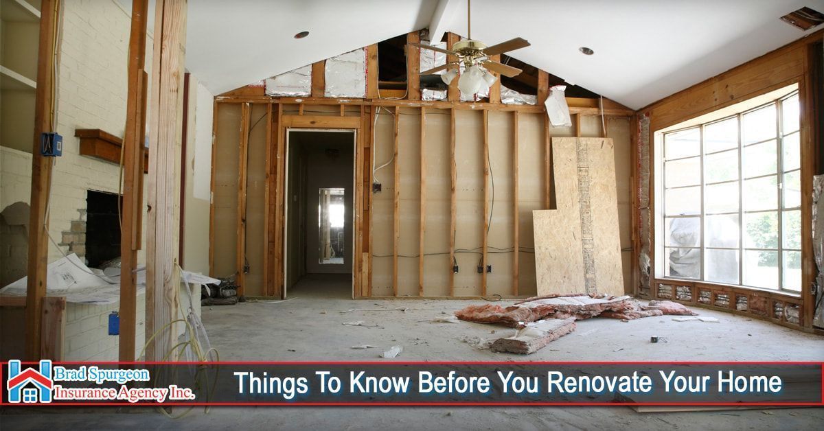 Interior view of a living room under major renovation, with exposed wood wall studs and a large window.