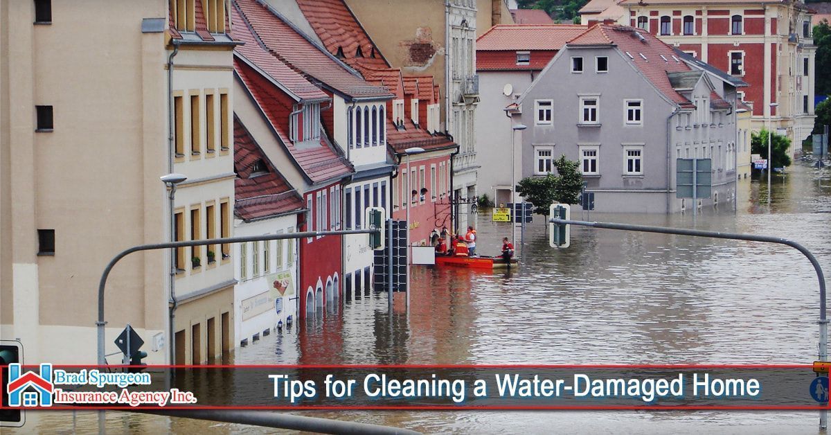 Floodwaters inundate a European-style street, where people in a small orange boat navigate past submerged building levels.