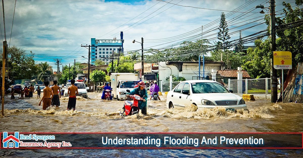 A flooded street with people wading through shallow water near a car