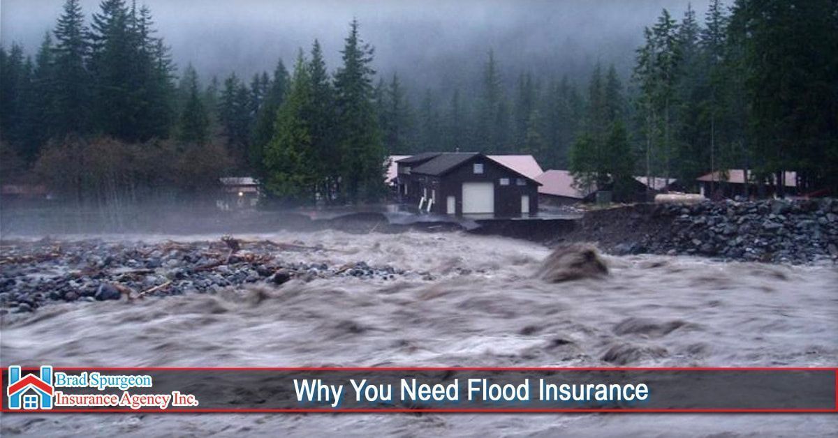 A dark, fast-moving, murky river floods a landscape with a house in the background.