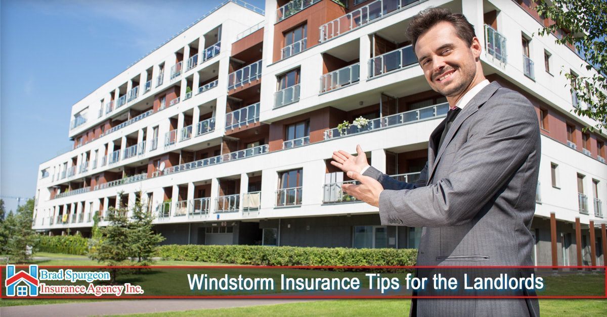 A smiling professional in a suit gestures toward a modern apartment building under a clear blue sky.