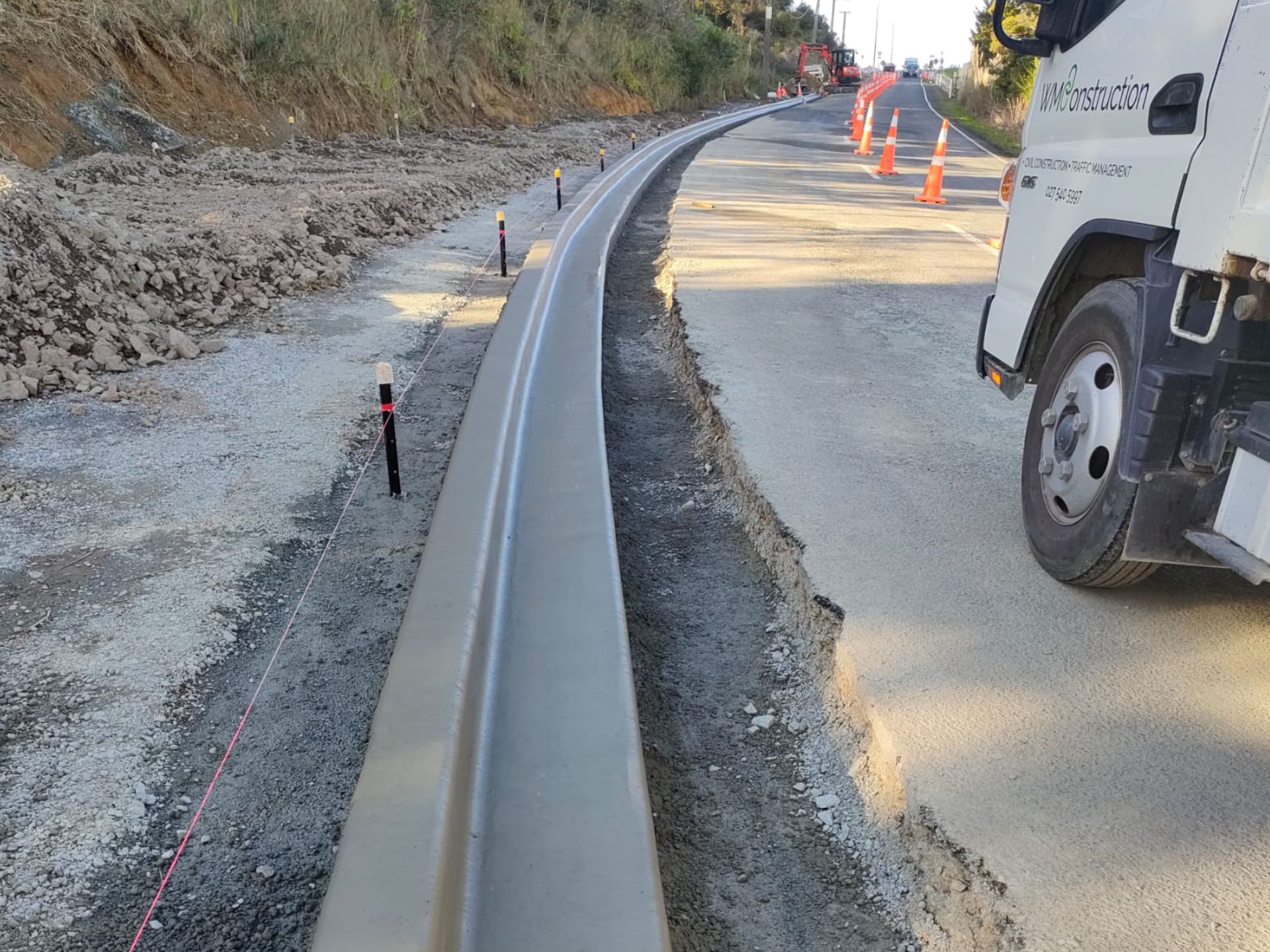 A WMConstruction white truck is parked next to a freshly extruded Kerb on the side of a road.